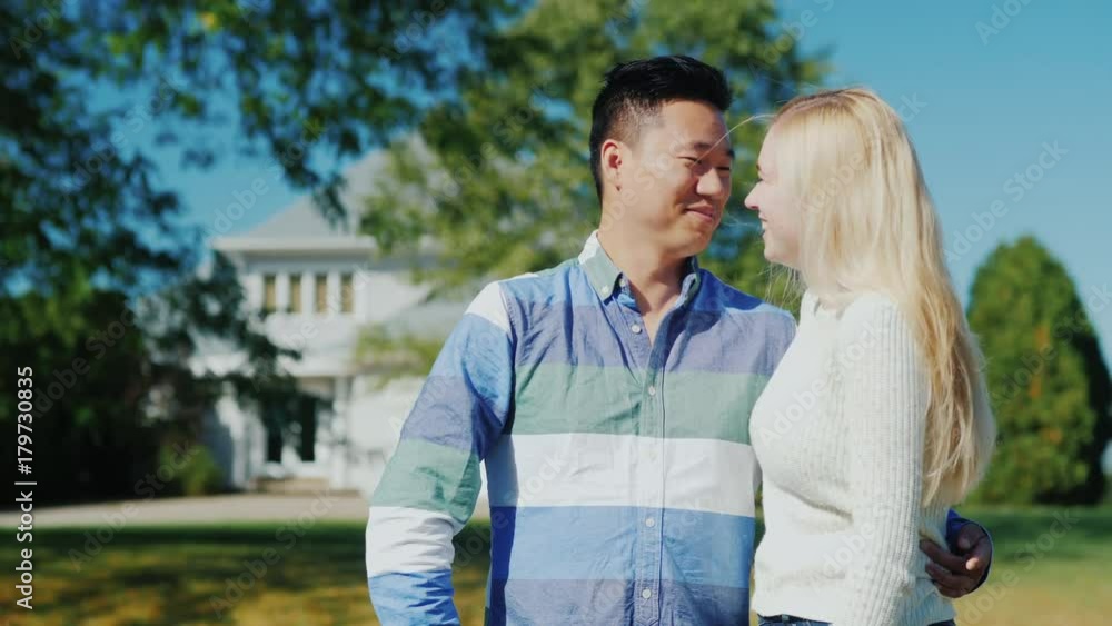 Happy young couple on the background of their American home. Chinese man and Caucasian woman Happy young couple on the background of their American home. Chinese man and Caucasian woman