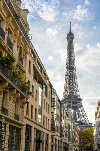 Photography View from an adjacent street of the majestic Eiffel Tower in its immediate neighborhood with typical parisian buildings in the foreground