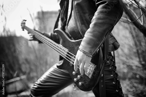 Rock guitarist outdoor. A musician with a bass guitar in a leath