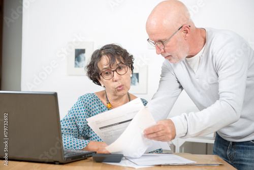Senior couple paying their bills with laptop at home