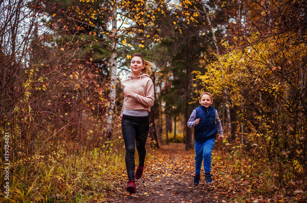 Little boy and his sister running in autumn forest