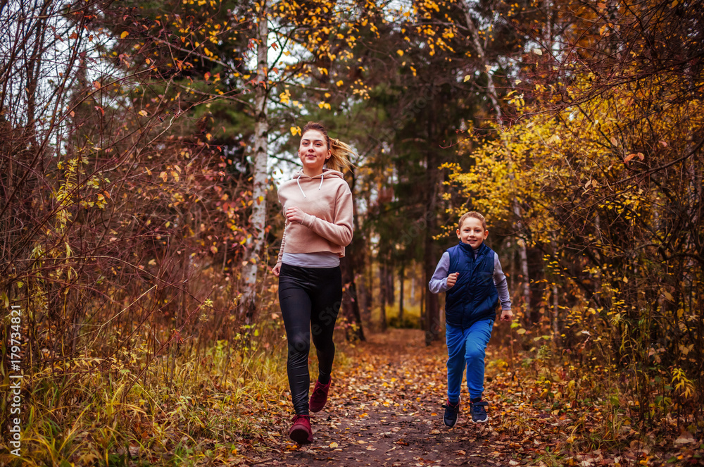 Little boy and his sister running in autumn forest Little boy and his sister running in autumn forest
