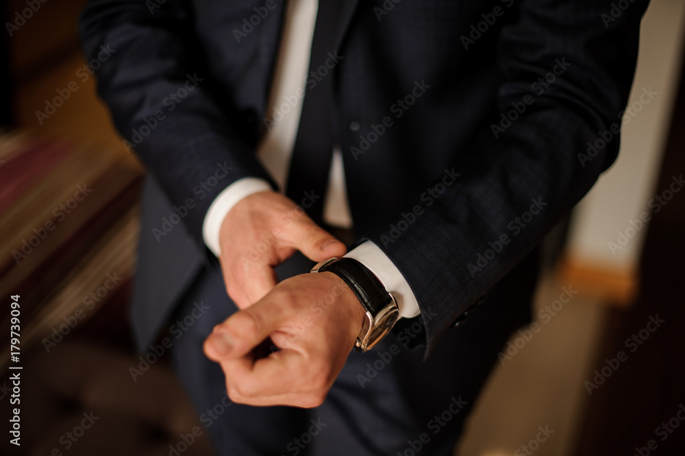 Grooms morning preparation. Handsome groom getting dressed in wedding suit