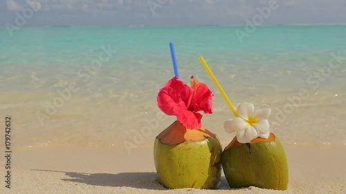 Tropical fresh coconut cocktail on white beach. Two coconut drinks on luxury tropical resort in Maldives island. Fresh green coconut cocktails on sandy Maldives beach with turquoise sea background.