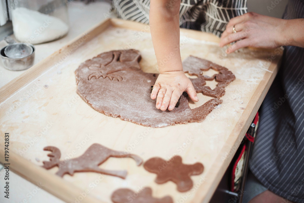 Close up of hands cutting shapes in gingerbread cookie dough. Shallow depth of field, copy space.