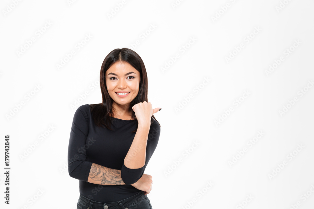 Cheerful young asian lady standing isolated pointing to copyspace. Cheerful young asian lady standing isolated pointing to copyspace.