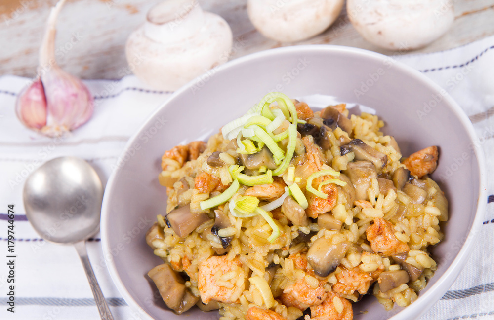 Risotto with mushrooms and chicken decorated with leek on a wooden background Risotto with mushrooms and chicken decorated with leek on a wooden background