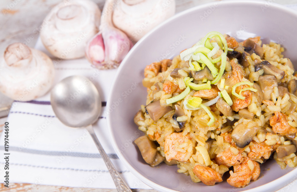 Risotto with mushrooms and chicken decorated with leek on a wooden background Risotto with mushrooms and chicken decorated with leek on a wooden background