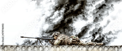 Fototapeta Naklejka Na Ścianę i Meble -  Sniper with large caliber rifle in action on the roof of riuned building
