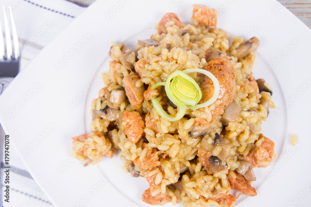 Risotto with mushrooms and chicken decorated with leek on a wooden background Risotto with mushrooms and chicken decorated with leek on a wooden background