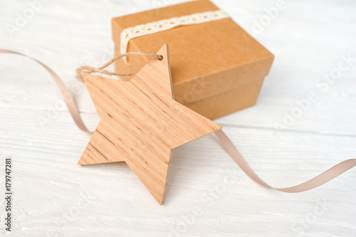 christmas wooden star tag with a gift on white wooden background. mockup for your text photo