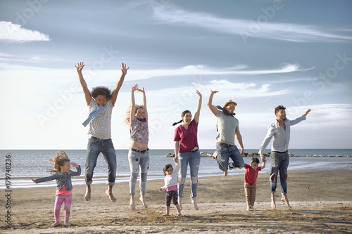 jumping on beach. mixed race kids with diverse young parents on beach having fun together.