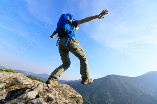 brave woman hiker walking to the cliff edge on top of mountain