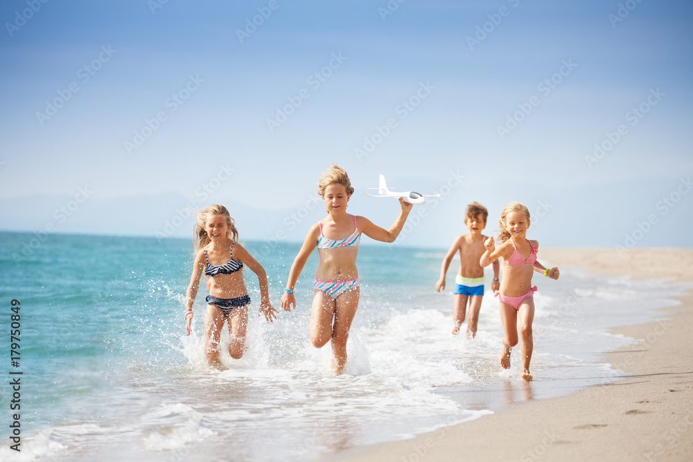 Kids running on coast and playing with toy plane