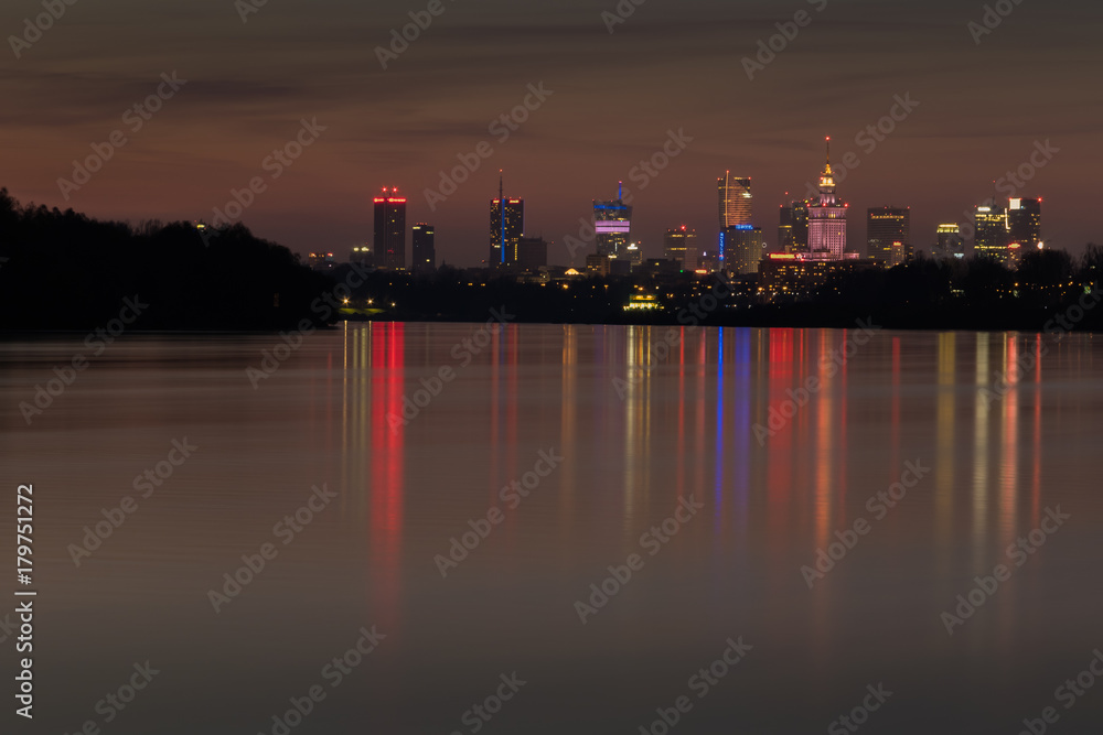 Colorful nocturnal skyline of Warsaw skyscrapers and their reflection in the Vistula River