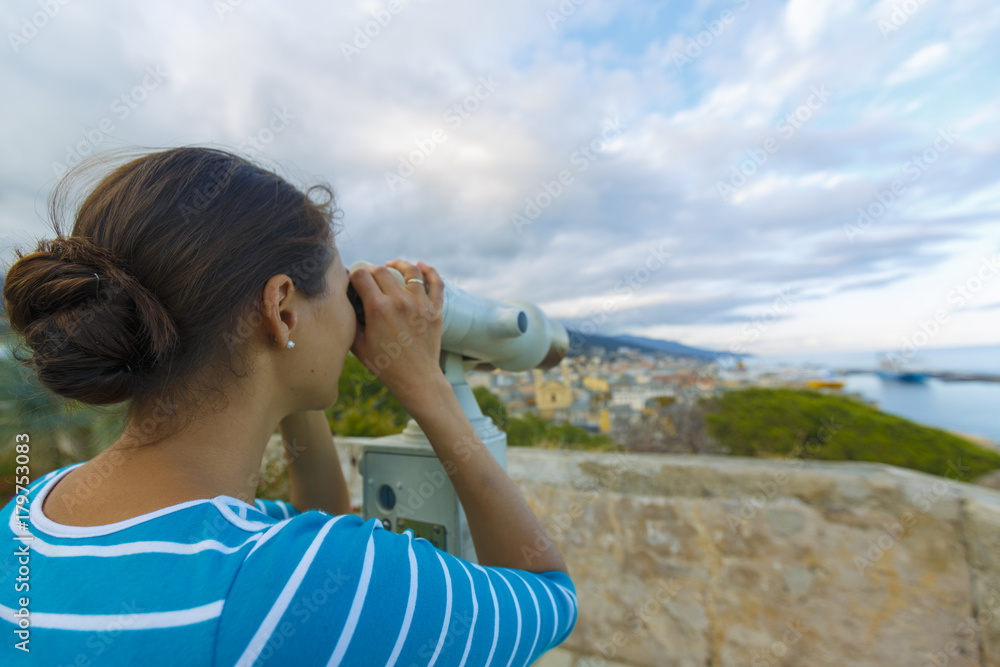 A woman with binoculars is looking at the Bastia city in France A woman with binoculars is looking at the Bastia city in France