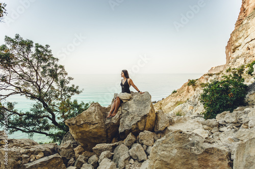 woman sitting on a stone against the sea