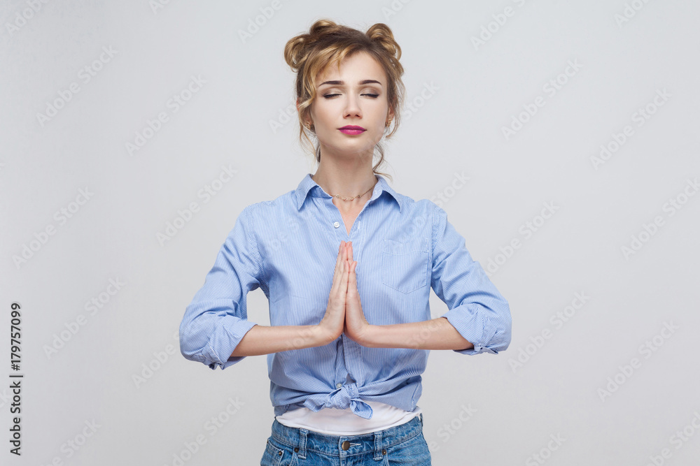 Woman holding hands in namaste or prayer, keeping eyes closed while practising yoga and meditating at home alone, having calm look on her face. Woman holding hands in namaste or prayer, keeping eyes closed while practising yoga and meditating at home alone, having calm look on her face.