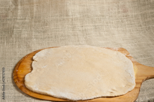 Baked homemade pizza dough / Baked homemade pizza dough rolled out onto a pizza peeling board