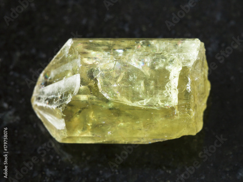 raw crystal of yellow apatite gemstone on dark