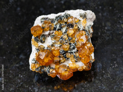 raw crystals of spessartine gemstone on dark photo