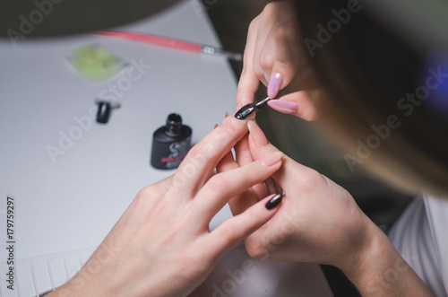 Manicurist hand painting client s nails. Professional workplace