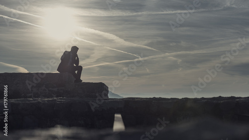 Fotografie, Tablou Thoughtful businessman sitting outdoors on a wall