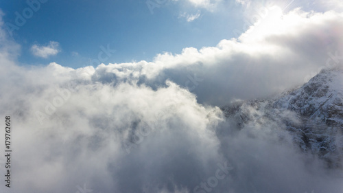 Aerial view of clouds circling around mountain ridge.
