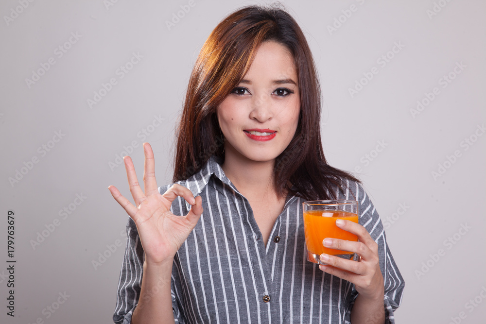 Young Asian woman drink orange juice show OK sign. Young Asian woman drink orange juice show OK sign.