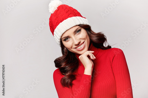 smiling beautiful girl in red christmas sweater and cap