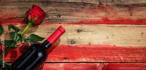 Valentines day. Red wine bottle and red rose on wooden background