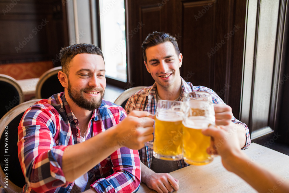 happy male friends drinking beer and clinking glasses at bar or pub