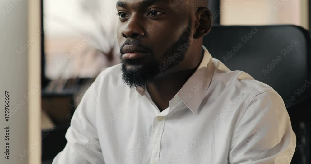 Portrait of face happy African American man with a beard working in an office focused on a job feel pleasure smile looking in monitor screen technology businessman successful business Slow Motion Shot Portrait of face happy African American man with a beard working in an office focused on a job feel pleasure smile looking in monitor screen technology businessman successful business Slow Motion Shot