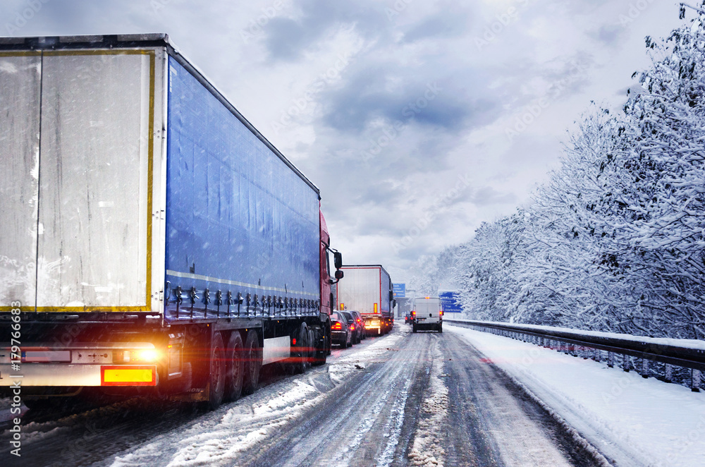 Obraz premium Wintereinbruch Schneeglätte LKW im Stau auf Autobahn
