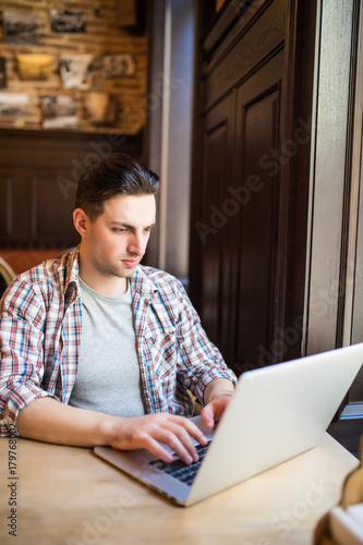 Handsome male entrepreneur typing message to content manager of website of marketing corporation on keyboard of laptop photo