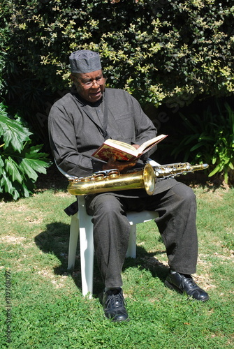 Photography Muslim jazz musician reading his book outdoors.