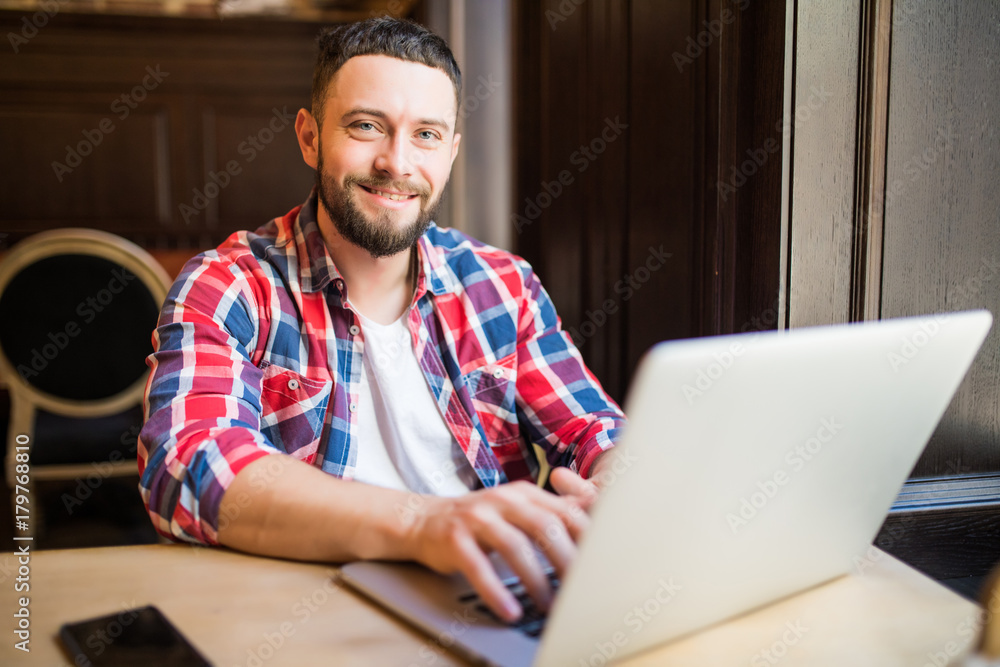 Shot of a young businessman working on his laptop in a cafe shop. Shot of a young businessman working on his laptop in a cafe shop.