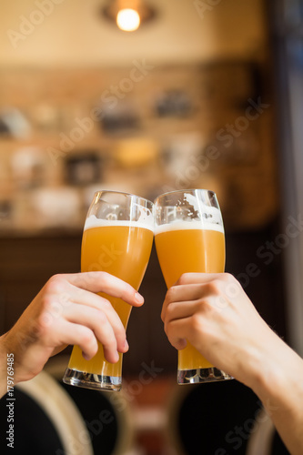 Close up og Mens hands cheers with beer in glasses in pub.