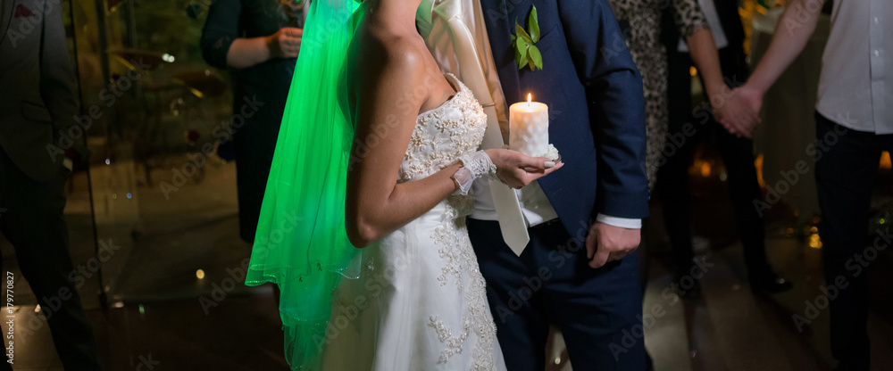 Candle in the hands of the bride and groom at the wedding