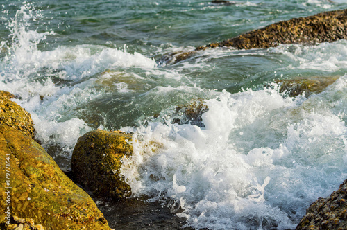 The waves breaking on a stony beach, forming a spray
