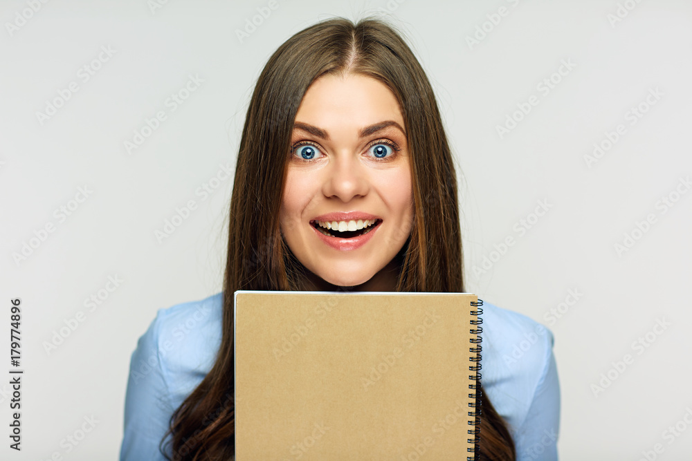 Surprising woman holding exercise book behind face. Surprising woman holding exercise book behind face.