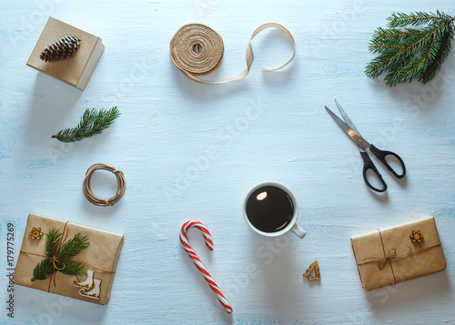 Christmas gift packaging composition. Christmas gifts, cup of tea, candy, fir branches, scissors, ribbon. Flat lay, top view
