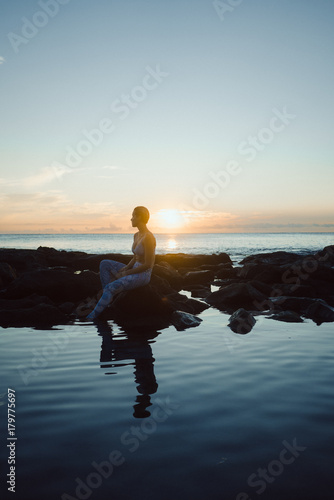 woman sitting by oceanside while sunset