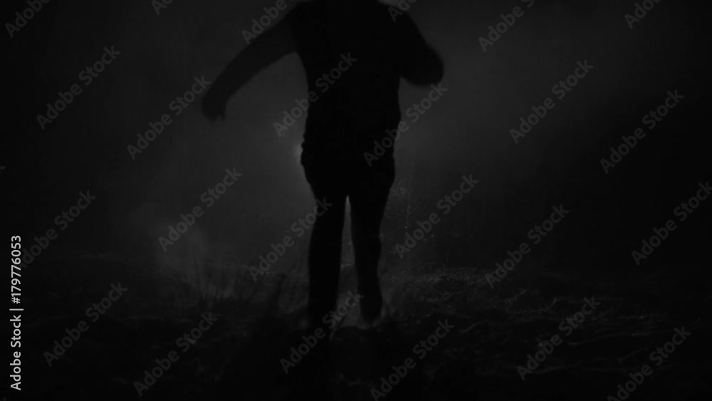Silhouette of a man running through the forest at winter night