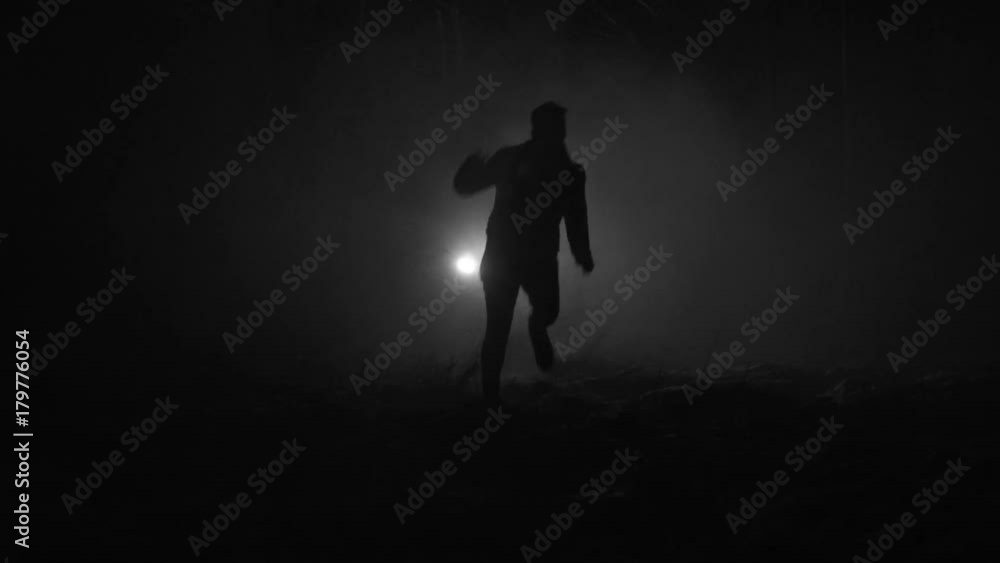 Silhouette of a man running through the forest at winter night Silhouette of a man running through the forest at winter night