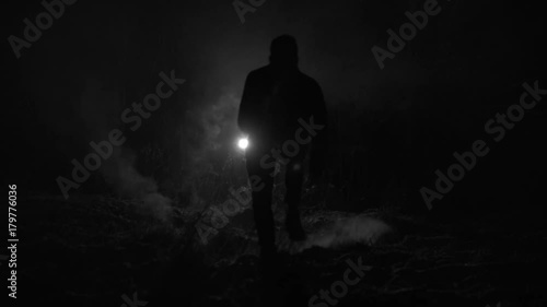 Silhouette of a man chased by light through the forest at winter night