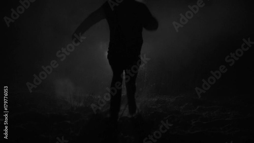 Silhouette of a man running through the forest at winter night