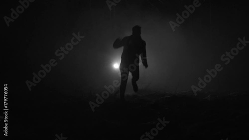 Silhouette of a man running through the forest at winter night