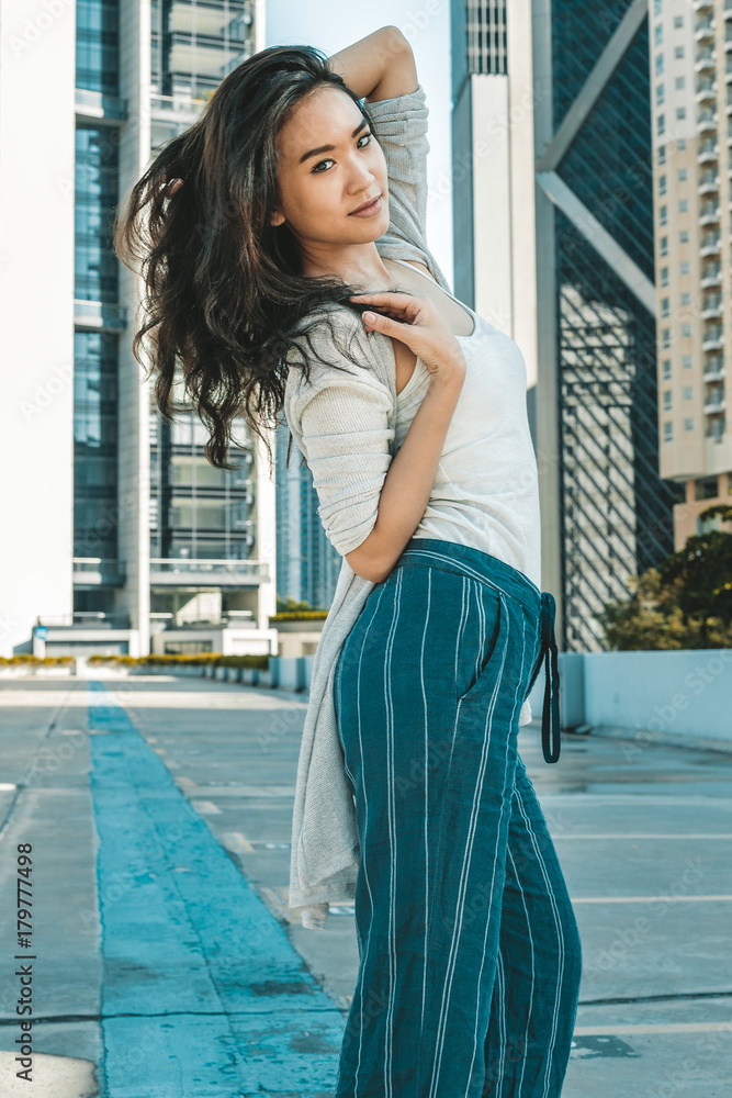 Young asian woman posing on rooftop in cityscape wearing casual clothes