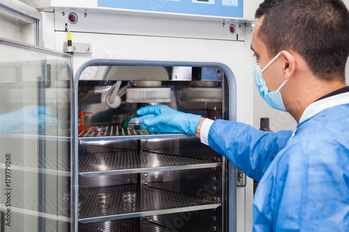 Young laboratory researcher introducing a petri dish into an incubator